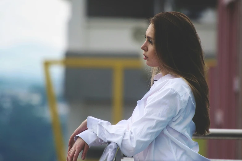 a woman sitting on top of a bench while wearing a white shirt