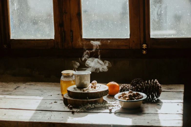 steaming tea on a table with pine cones and fruit