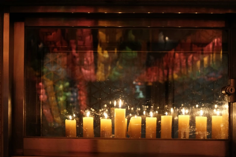 a group of yellow candles are next to a window