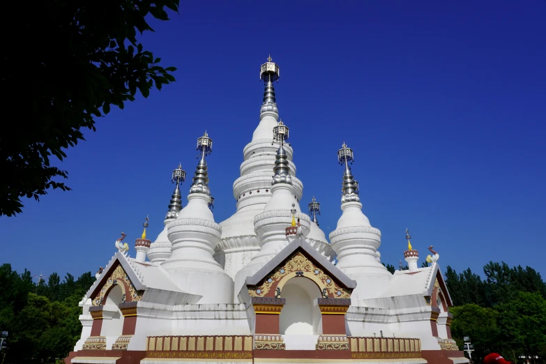 a temple with white spires that overlooks trees