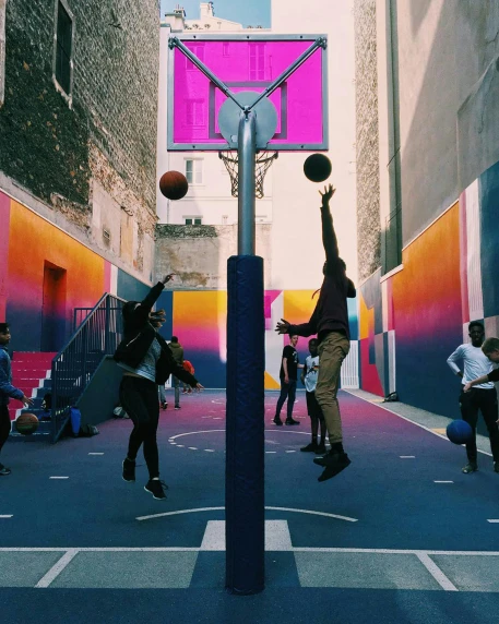 young men playing a basketball game on an alley