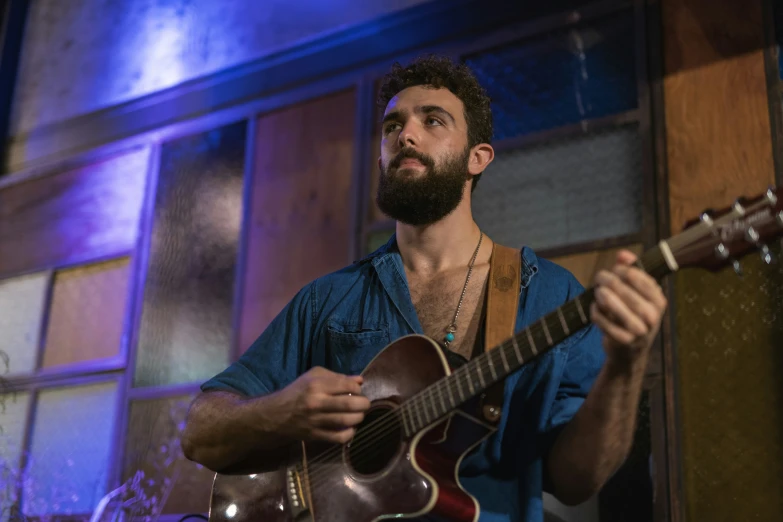 a man with a beard playing an acoustic guitar