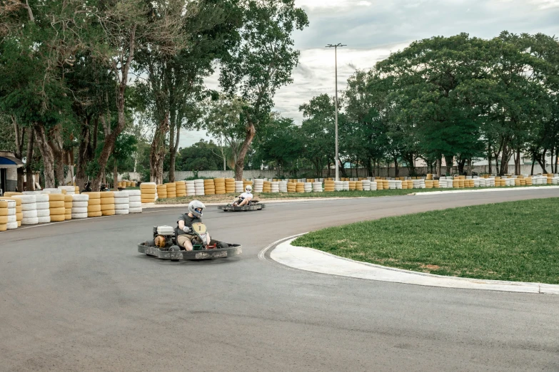 people racing motorcycles down the street by some trees