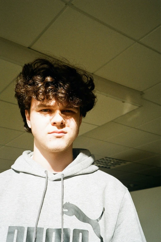 young man with face and hooded sweat shirt in large room