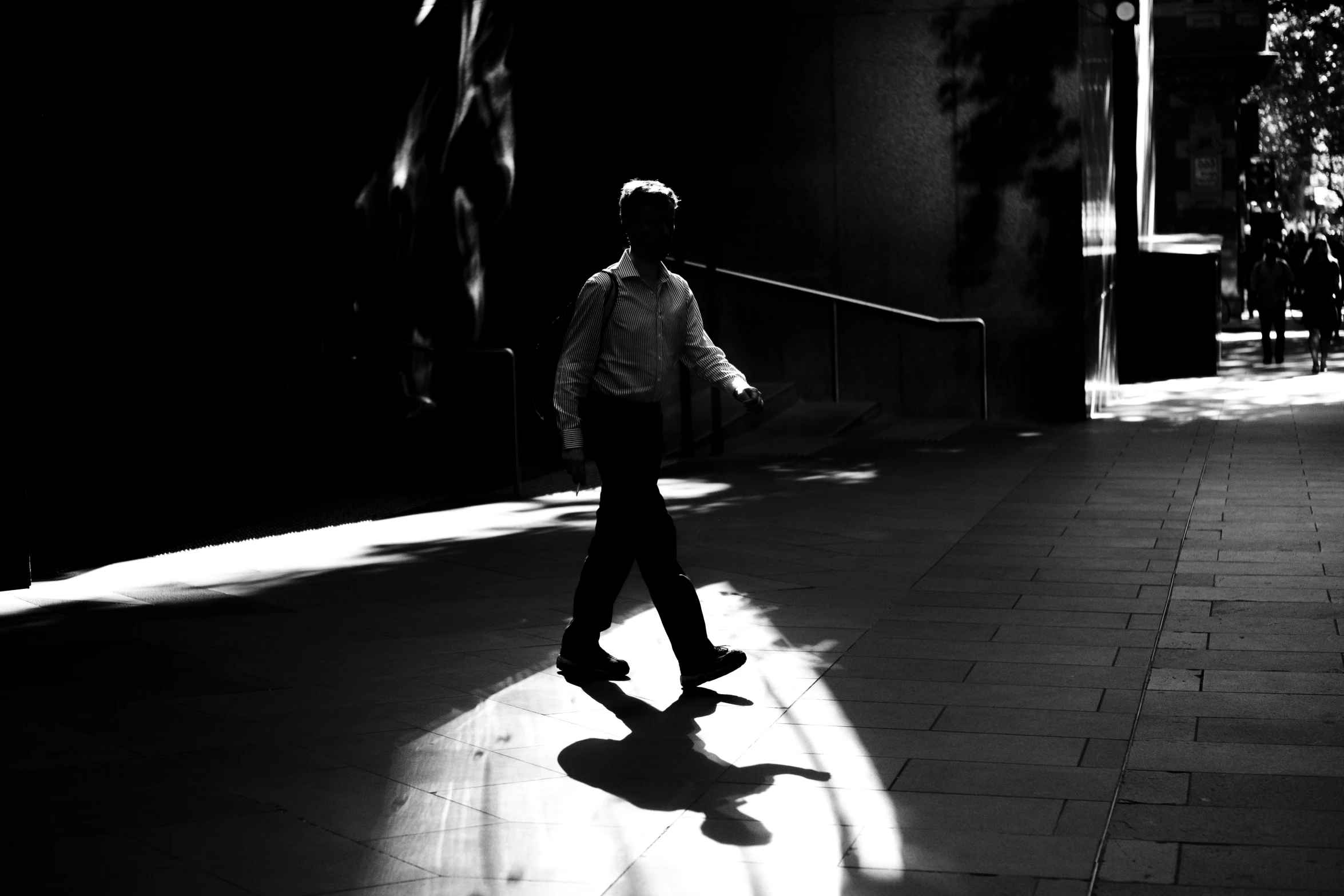 a man walking down the street holding on to his skateboard