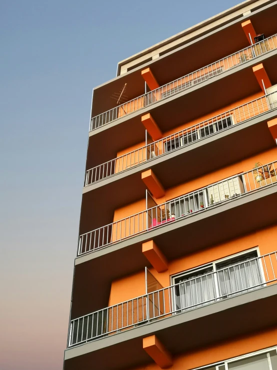 a big building with orange balconies and metal balconies