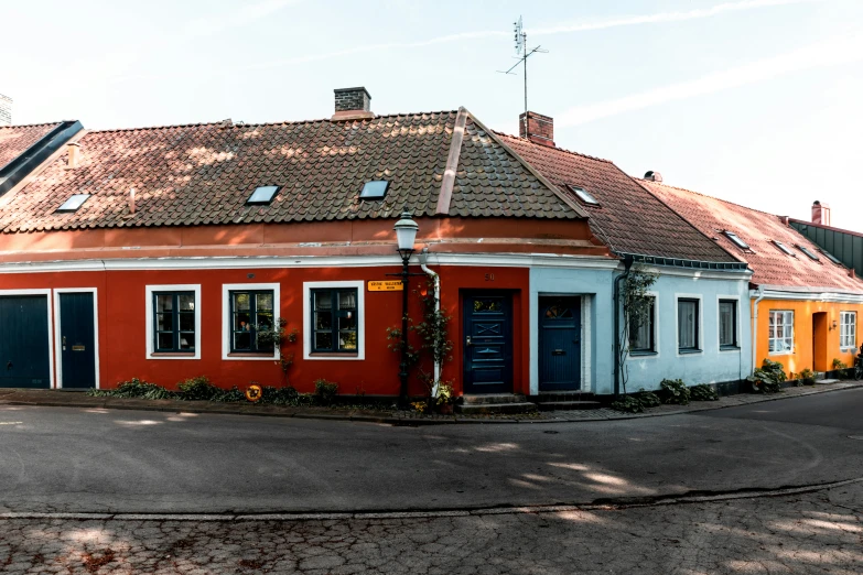 an orange, white and blue house sitting on the side of a road