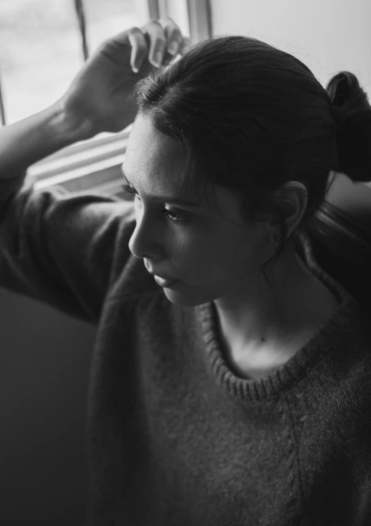 a woman leaning against the window with her head tilted