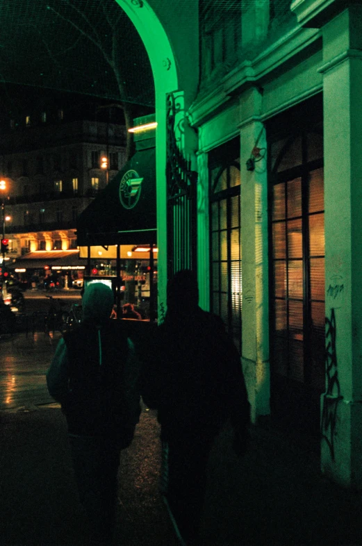 two people are walking on the sidewalk with luggage