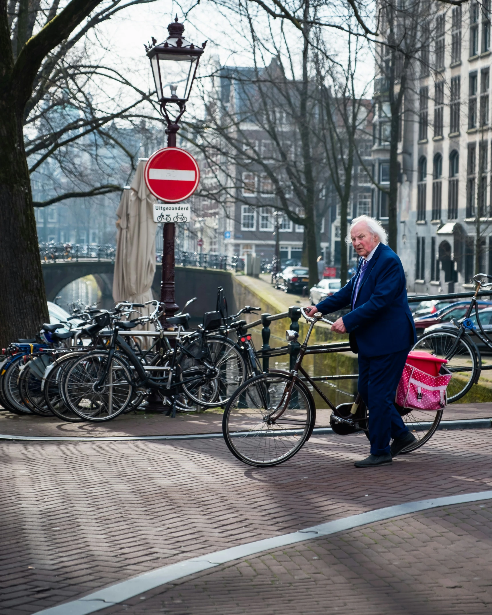 a man in blue suit on a bicycle next to many parked bikes