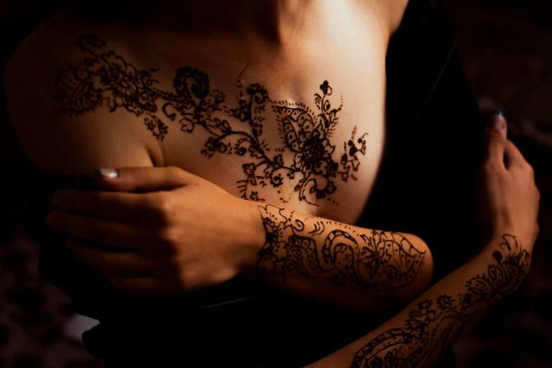 a women with hendi flowers on her arms and arm tattoo