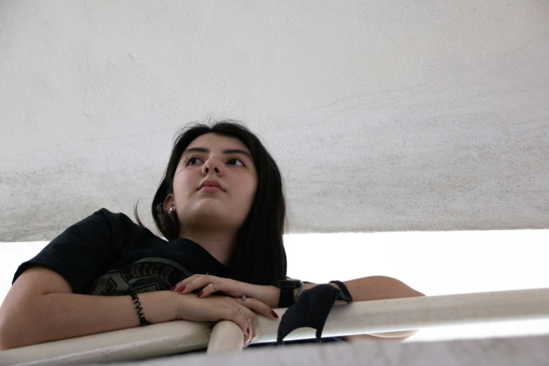 a woman with her arms around her knee sits on top of a pole