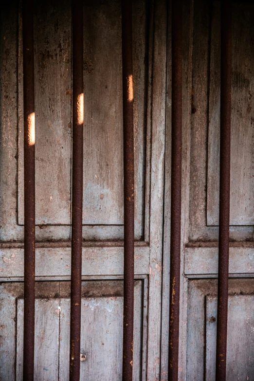 a group of rusty bars on a brown wooden wall