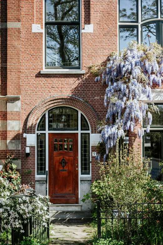 a brick house with a large purple flower bush next to it