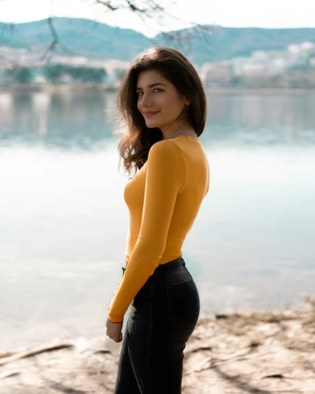 a woman posing with her hands on her hips next to water