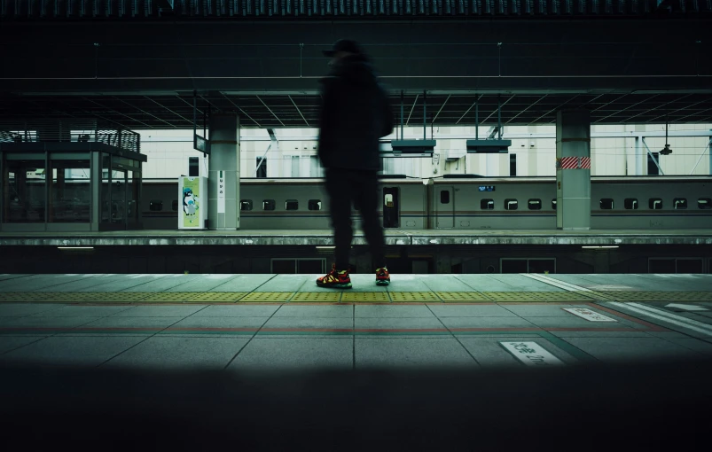 a man in a dark subway station with a red suitcase