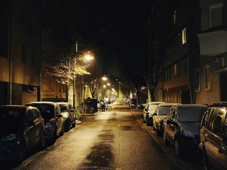 the dark street at night is lined with parked cars