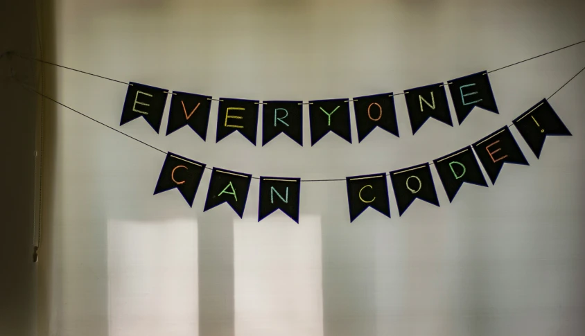 a banner that says everyone can code is hanging from a wall