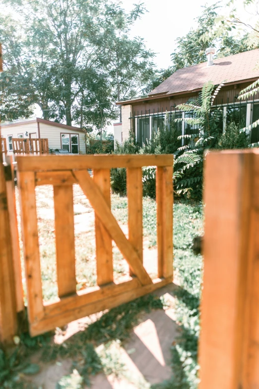 an open gated wooden fence on a small grass covered yard