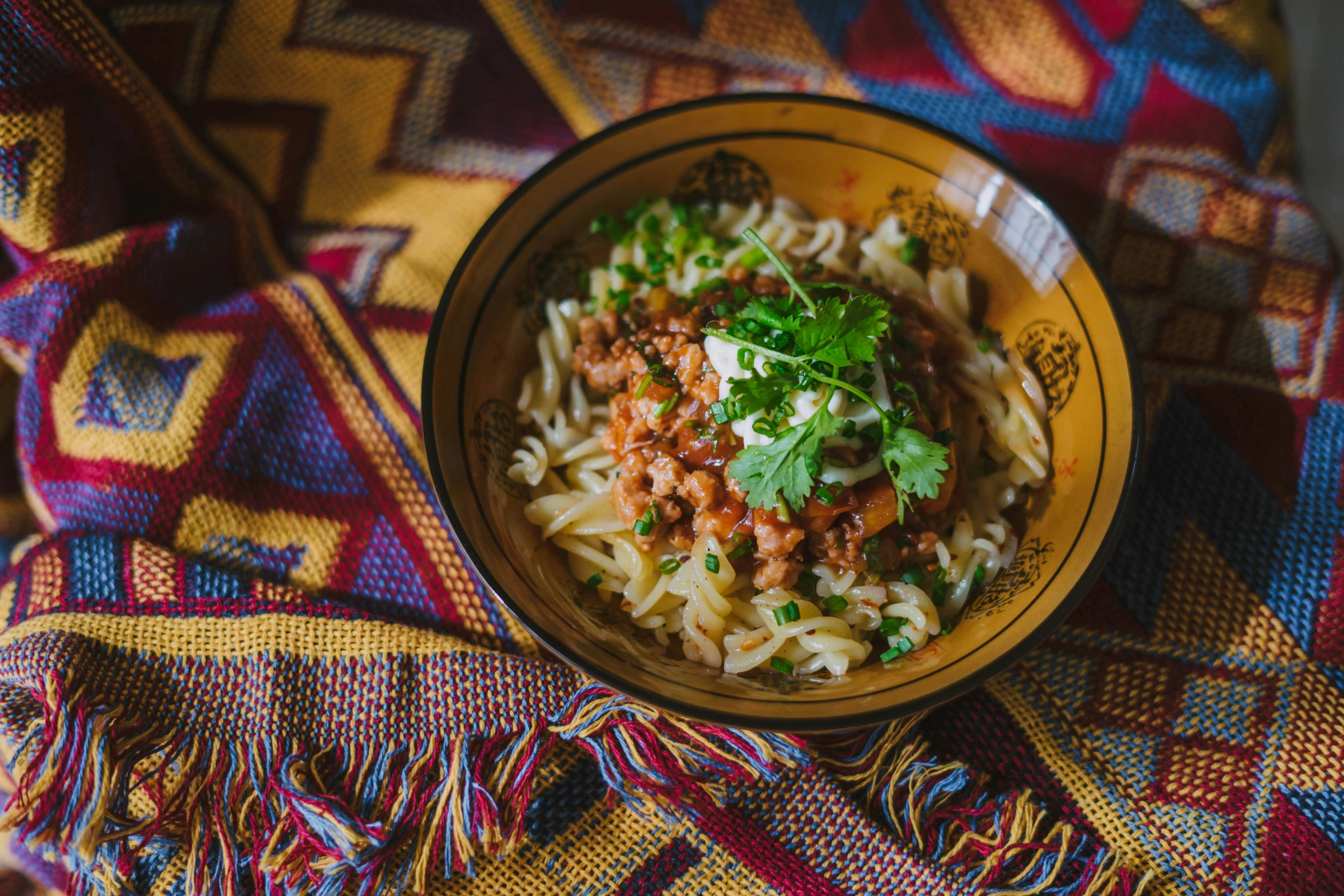 a dish of pasta on top of a colorful tablecloth