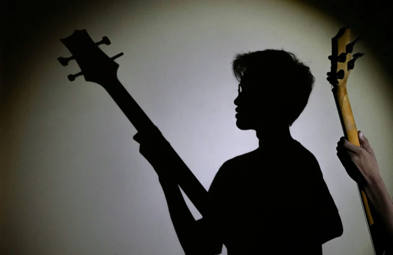 a man holding his guitar and pointing at a po on the wall