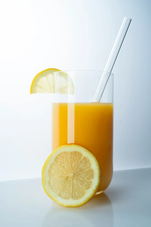 a glass with two straws next to a lemon