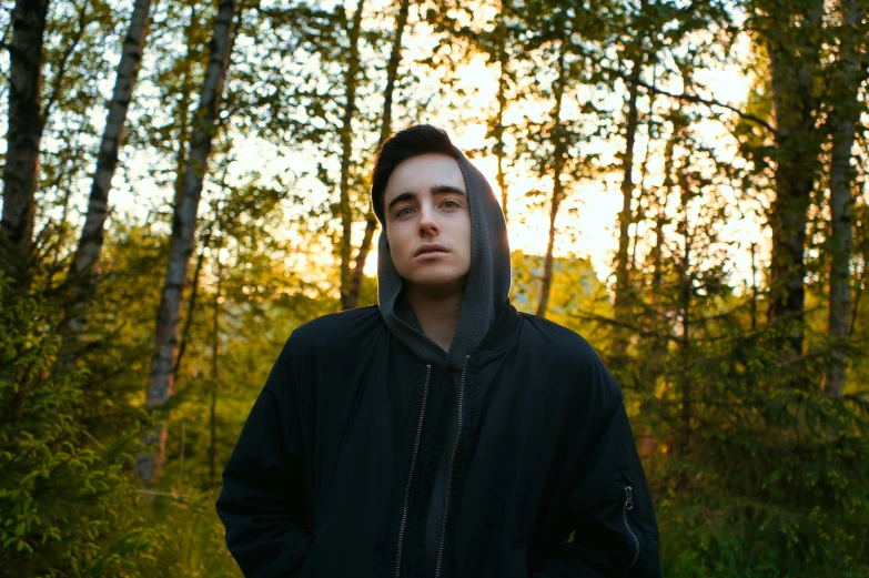 a man standing in the woods in front of some trees