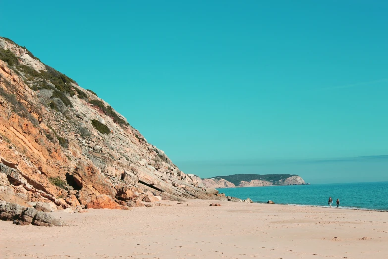 the two people walk on the beach in the sun