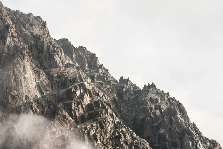 large and thick rock mountains with clouds moving through the air