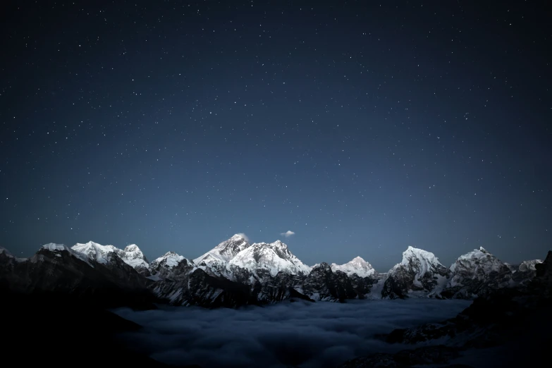 a night sky with a few stars above a snowy mountain