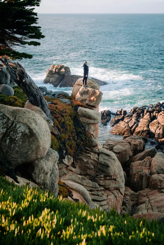 person standing on rocks by ocean in a rocky area