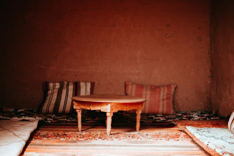 this room has a table, carpet, and several pillows