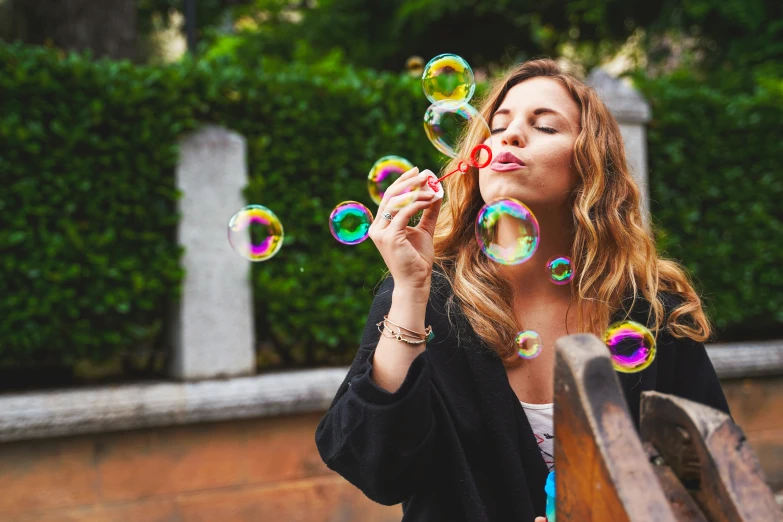 a woman blowing soap bubbles on top of her face