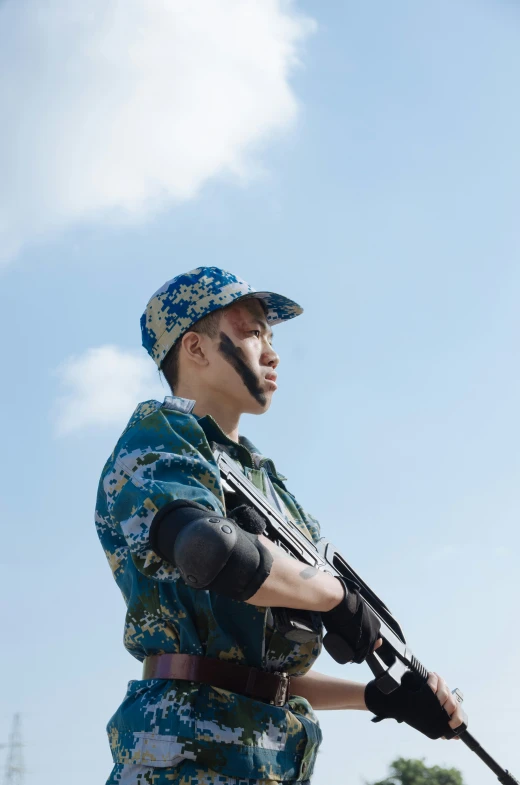 a man in uniform holding a gun under a partly cloudy sky