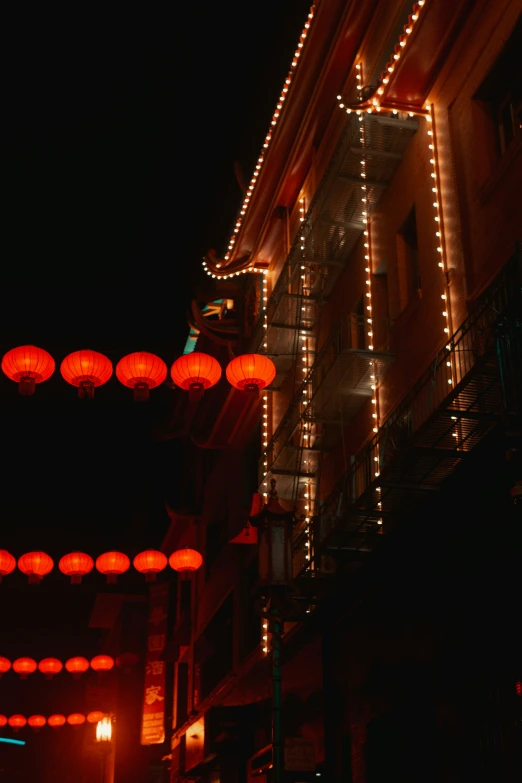 chinese lanterns lit up in the night sky above an urban street