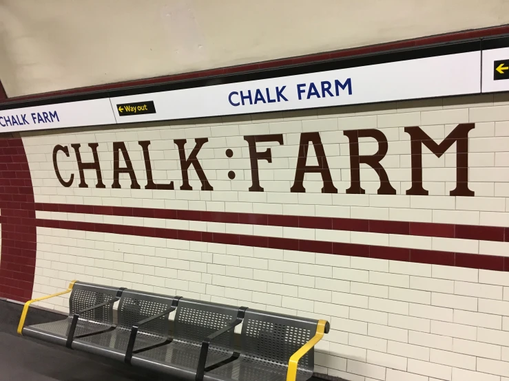 a subway station wall painted in maroon and white with a bench underneath