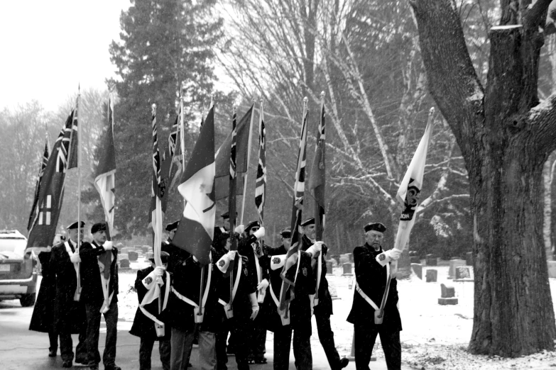 several men holding flags walking down a sidewalk in the snow