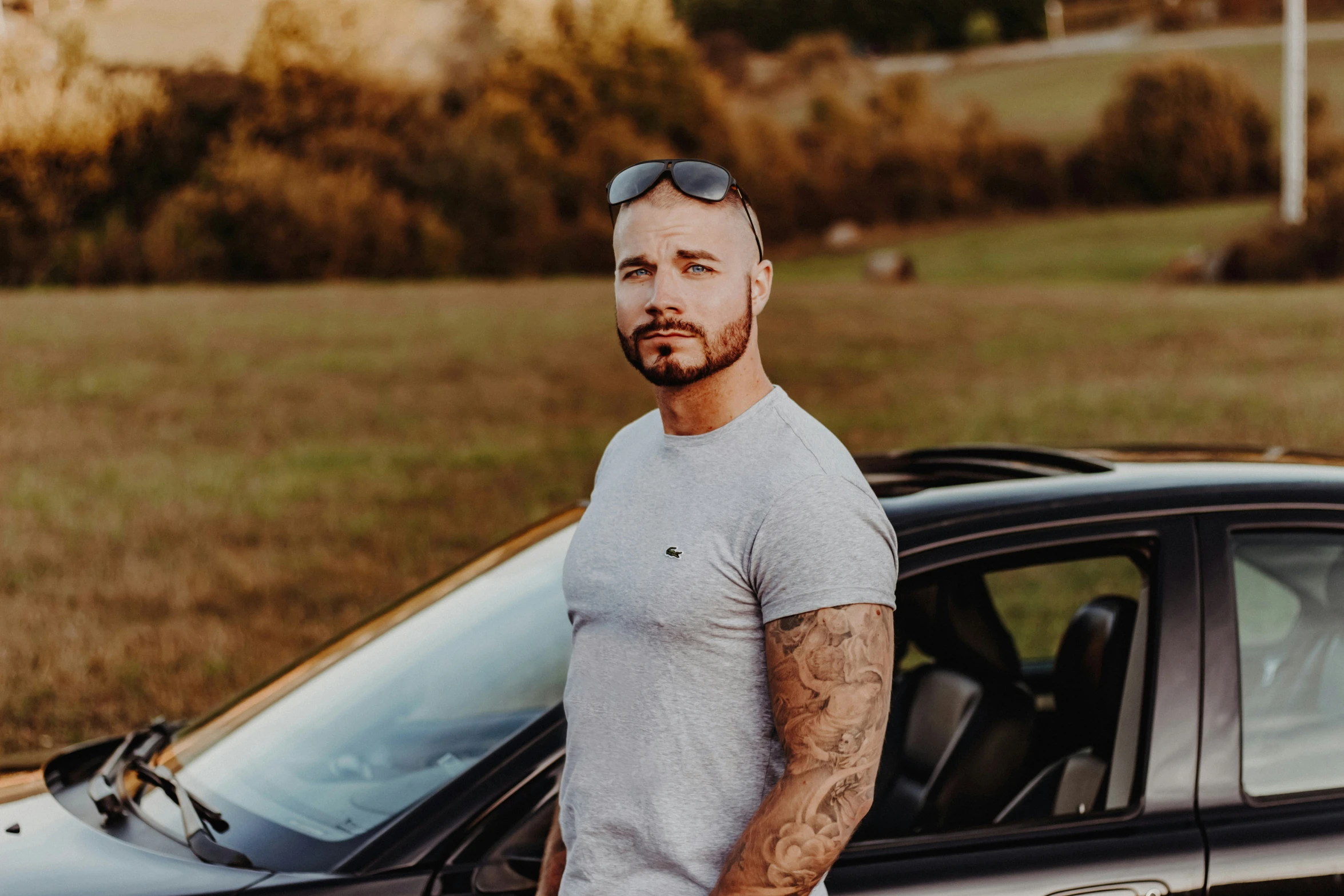 a man with sunglasses stands near a black car