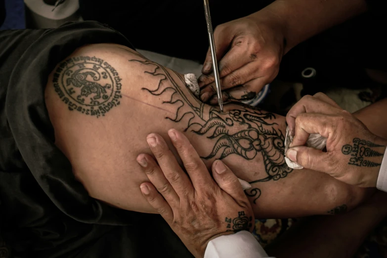 an asian man getting his tattoo done by someone