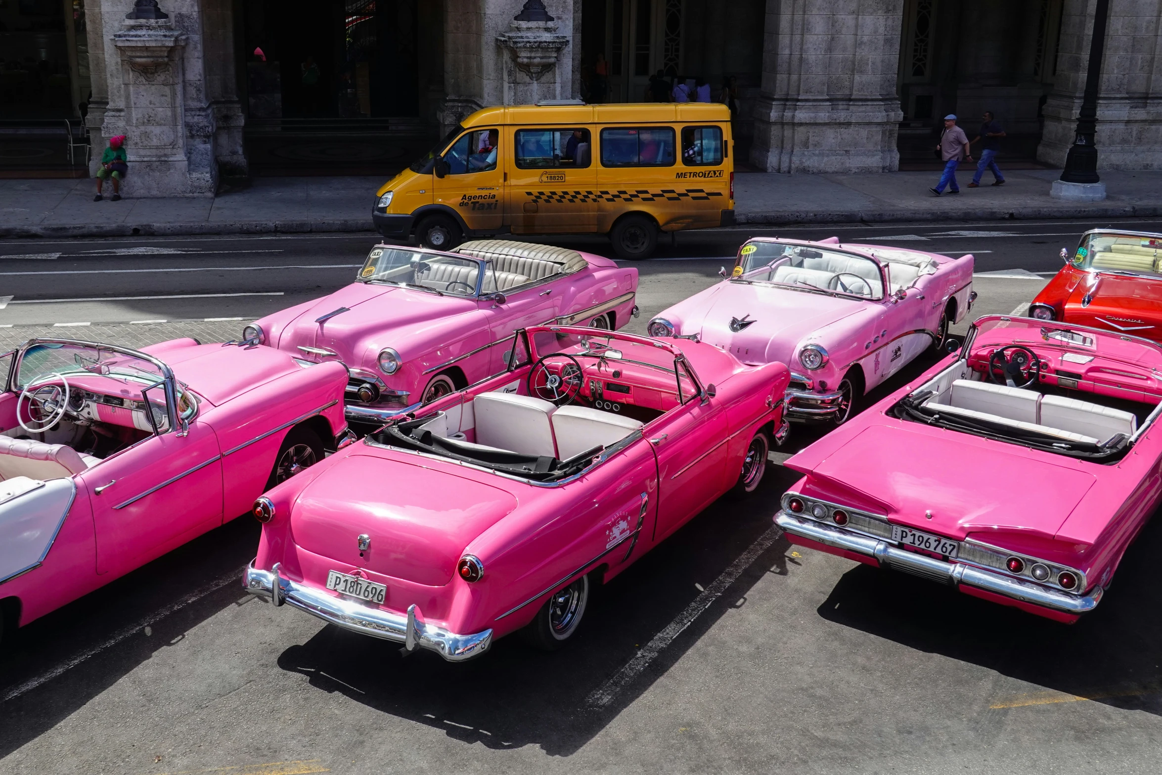 a bunch of pink cars are parked on the street