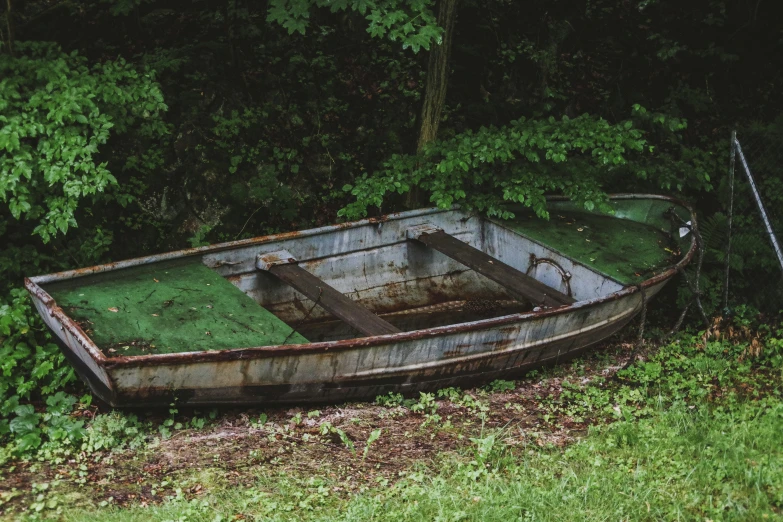 an old wooden boat is sitting in some weeds