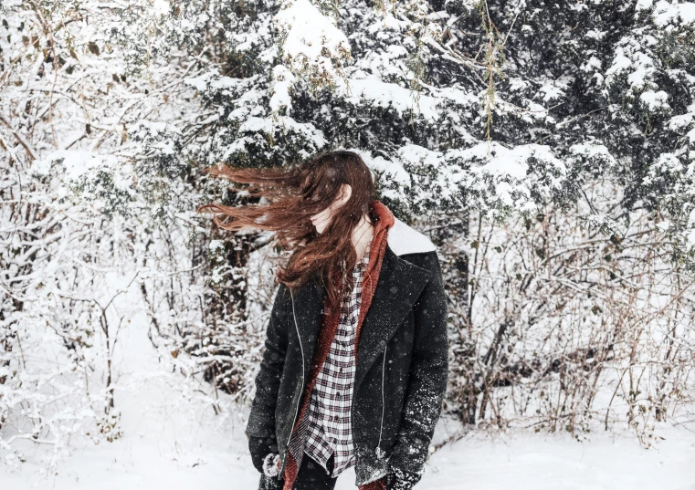 a girl standing in the snow near the trees