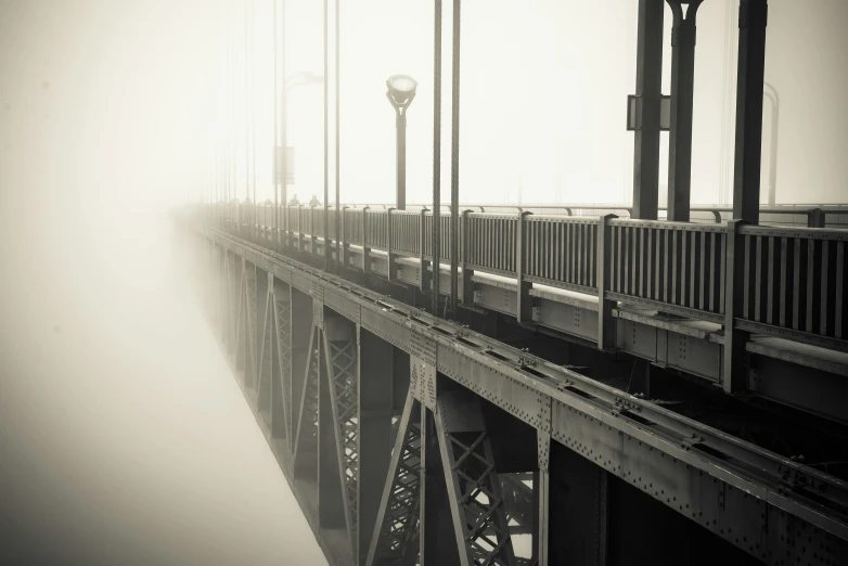 a foggy suspension bridge with lights on and poles