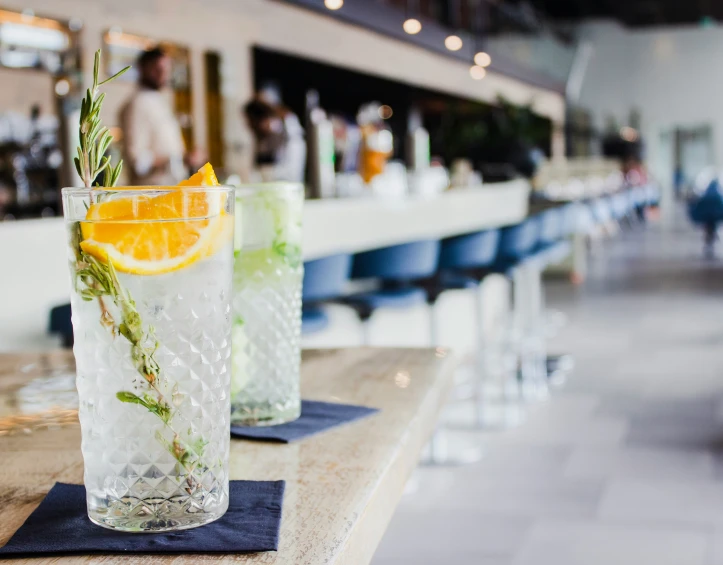 two long cups with garnish on them sit on the bar