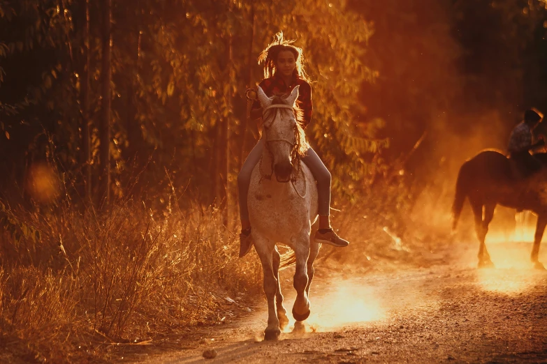 two horses are running along the trail with people riding them