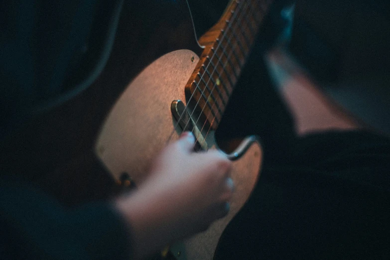 a person playing an acoustic guitar with the help of another person