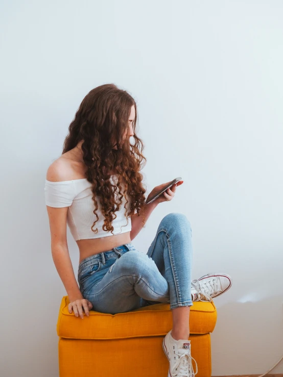 a girl sitting on a couch using her phone