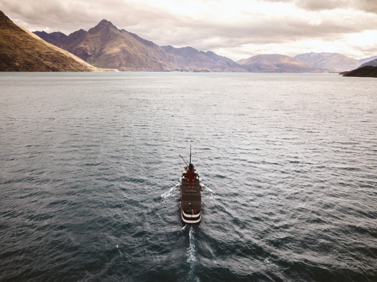 boat in calm water on cloudy day with mountains in the background