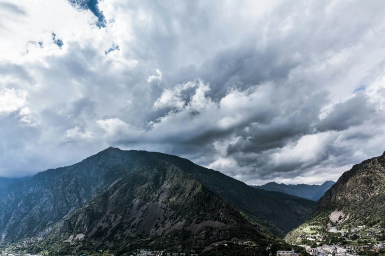 a cloudy landscape with mountains and buildings