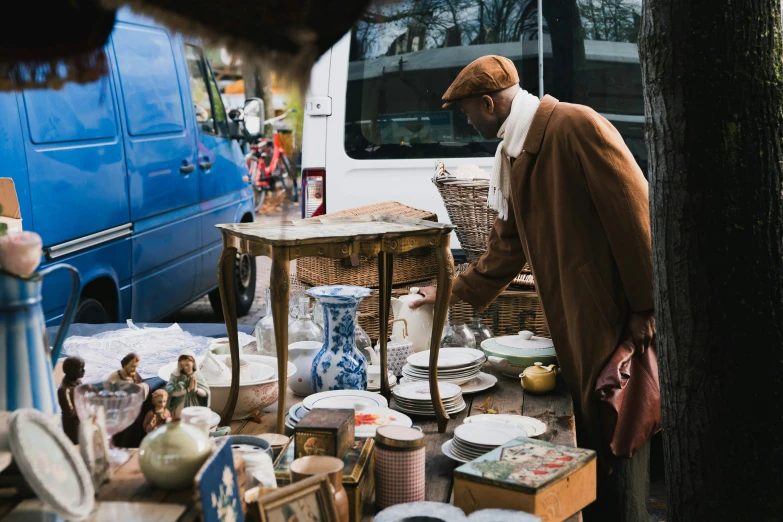 the man is selling porcelain dishes and other things to buy